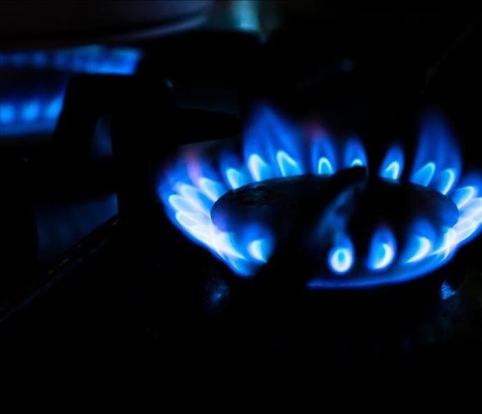 Bright blue flames erupt from a stovetop burner.