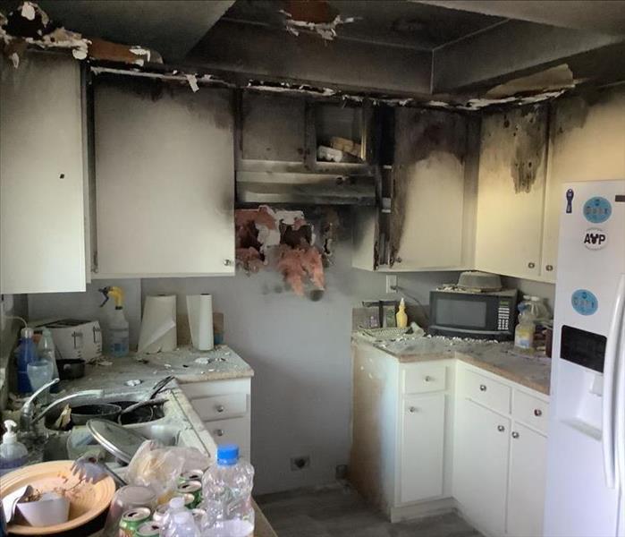 white kitchen cabinets and counter top burnt due to a stove fire contained to one area 
